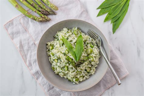 pogled na servirano rižoto z divjimi šparglji in limonino lupinico