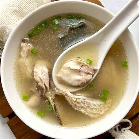 Thematic photo of a bowl of clear Chinese fish soup with herbs