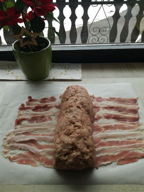 Mesna štruca, ovita v slanino, postavljena v pekač, pripravljena za peko.