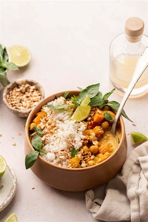 Različne posode s piščančjim curryjem in rižem, posutimi s svežim koriandrom