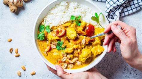 Slika kuhanega piščančjega curryja s kokosovim mlekom, postreženega z rižem in posutega s svežim koriandrom