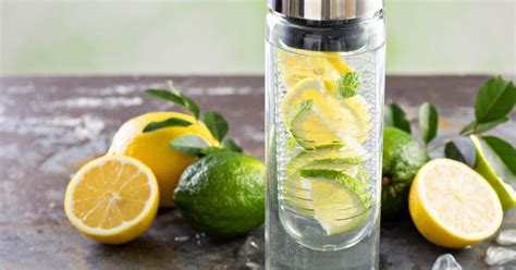 fotografija domačega limoninega sirupa v steklenici z rezinami limon in meto