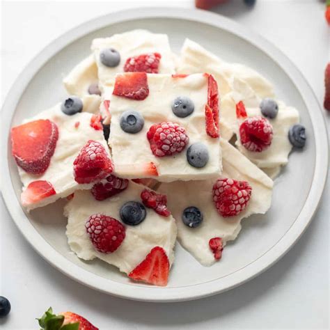 A frozen yogurt bark with mixed berries and almonds on parchment paper.