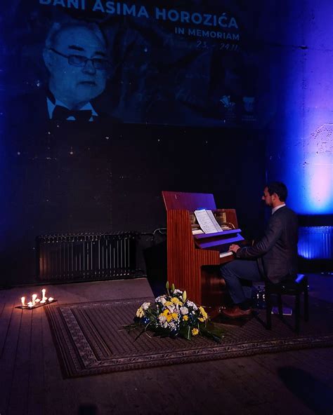 Fotografija: dvorana polna ljudi med klavirskim recitalom, poudarek na elegantni obleki pianistke