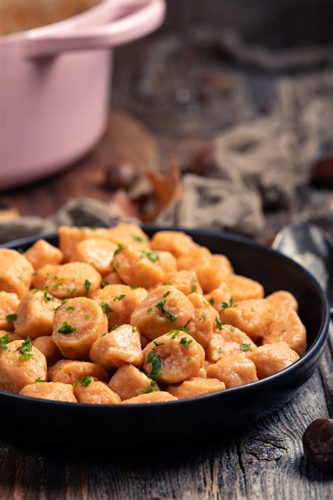 pogled na pripravljene njoke iz sladkega krompirja v masleni omaki, okrašene s peteršiljem in parmezanom