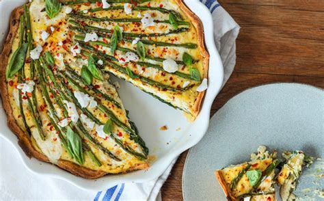 Thematic photo of a beautifully presented slice of vegan asparagus pie on a plate, garnished with fresh herbs.