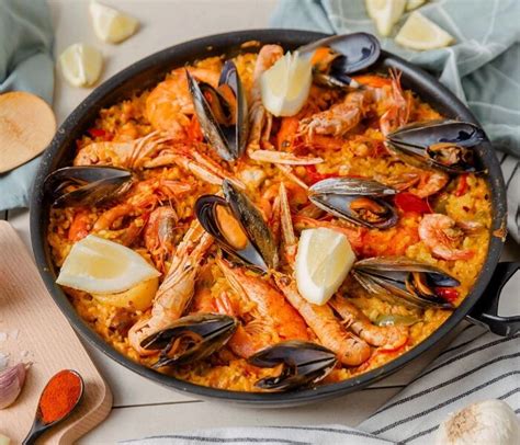 Pripravljena mešana paella, okrašena z limono in peteršiljem