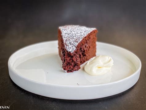 Fotografija kosa torte z rdečo peso in smetanovim prelivom, na beli plošči