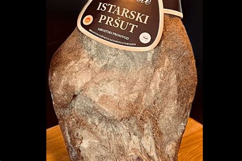 Tematska fotografija: celo stegno Kraškega pršuta z oznako ZGO, obešeno v zorilnici