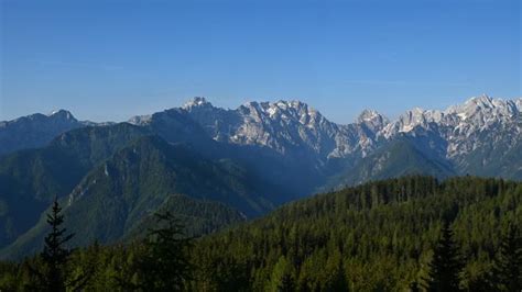 Panoramski pogled na Logarsko dolino z zasneženimi vrhovi Kamniško-Savinjskih Alp v ozadju