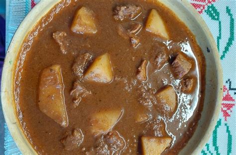 Ilustracija bograča z različnimi vrstami mesa in krompirjem, kuhanimi skupaj.