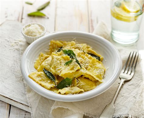 Prikaz kuhanih raviolov z žajbljevim maslom, orehi in parmezanom