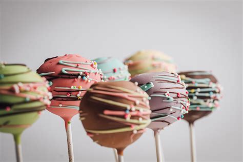 Ilustracija pisanih cake popsov na palčkah.