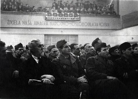 Zgodovinska fotografija Dvorane AVNOJ-a v Jajcu z jugoslovanskimi zastavami in Titovim naslonjačem
