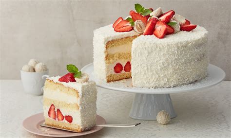 fotografija elegantne Raffaello torte, posute s kokosom in okrašene z Raffaello kroglicami