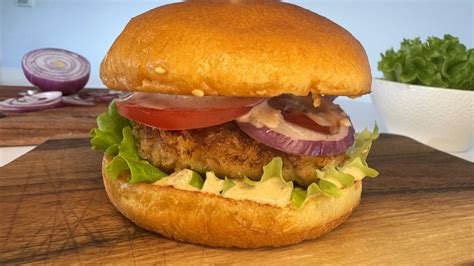 Sočen piščančji burger z natrganim mesom, čebulno marmelado in hrustljavo piščančjo kožico