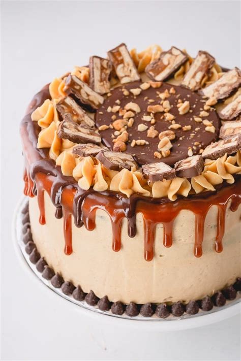 Infographic showing layers of a Snickers cake: biscuit, caramel, cream, peanuts