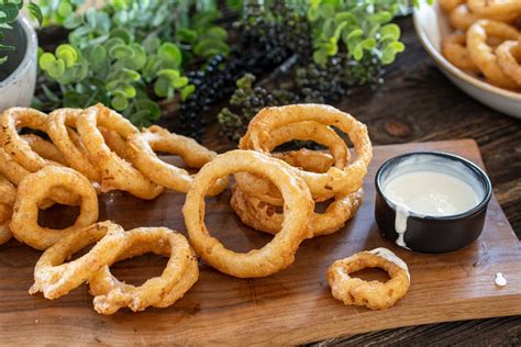 Čebulni obročki v hrustljavem pivskem testu, postreženi s solato in omako