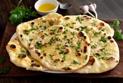 Tematsko foto: Sveže pečen indijski kruh Naan na krožniku z zelišči